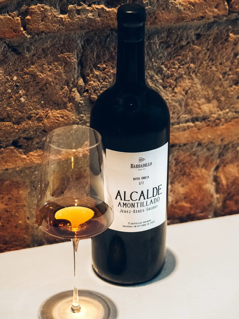 Una copa de amontillado junto a su botella, ante el ladrillo