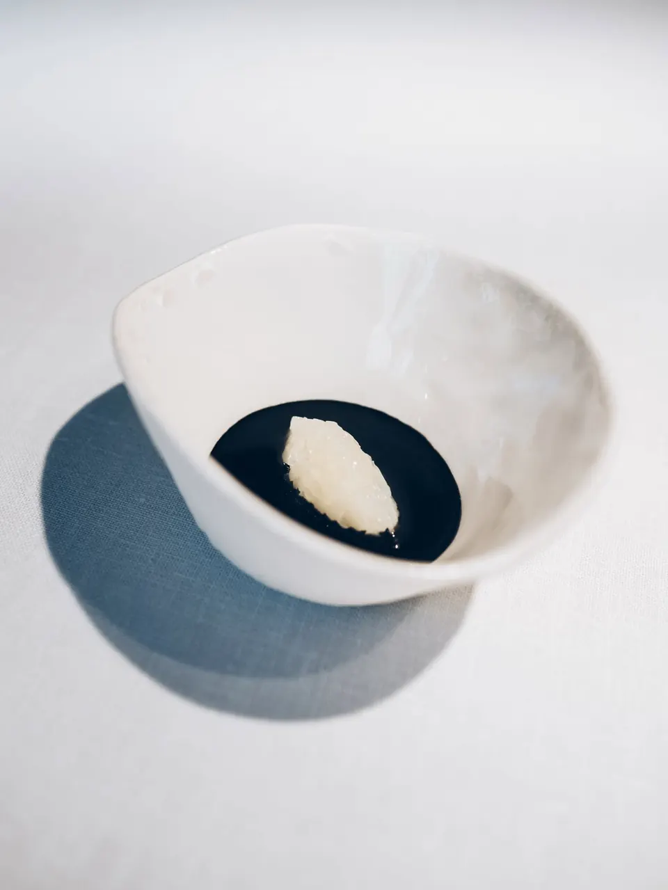 Un cuenco blanco con una salsa negra y una quenelle