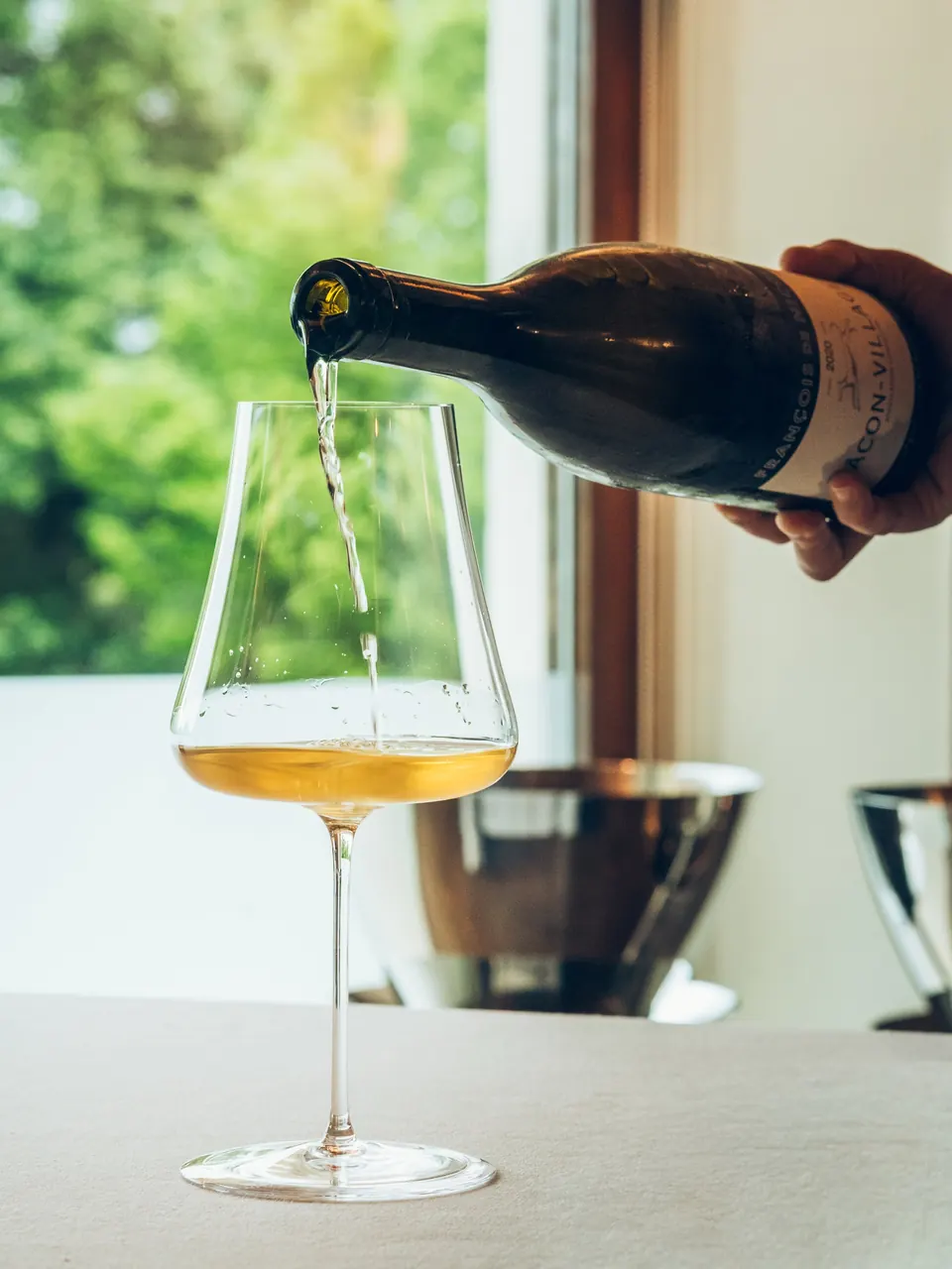 Se sirve vino blanco en una copa junto a una ventana