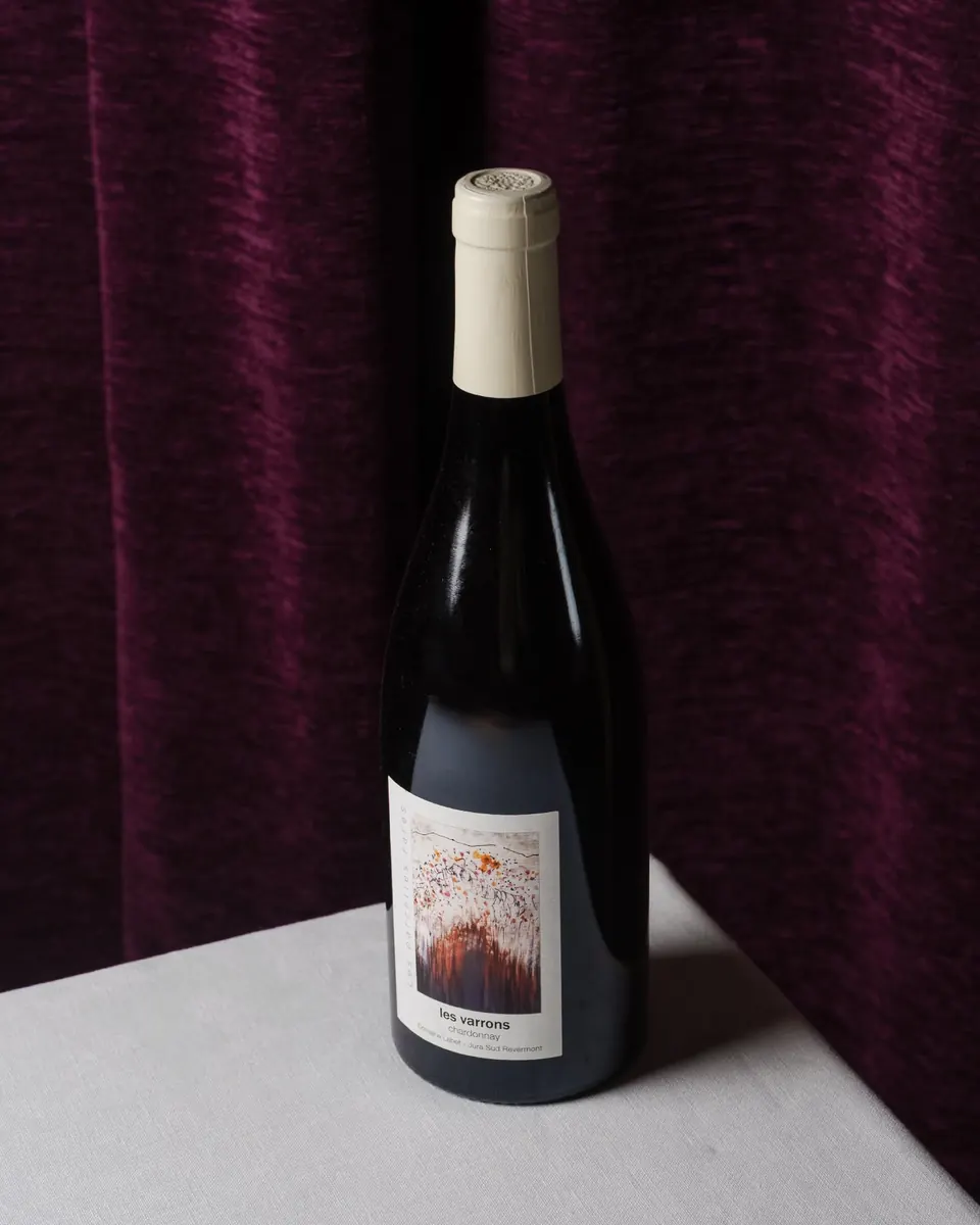 Una botella de vino blanco ante la cortina de terciopelo